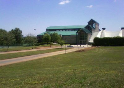 A modern building with green roofs surrounded by a lawn and trees, under a clear blue Maryland sky.