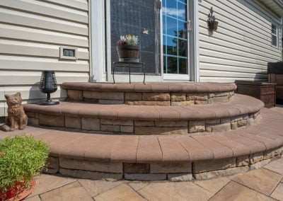 Stone steps leading to a patio door with potted plants and a cat statue on the side, reminiscent of Frederick's charming ambiance in Maryland.