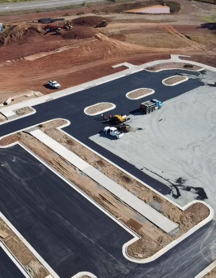 Aerial view of a construction site with newly paved roads, vehicles, and equipment on dirt and asphalt.