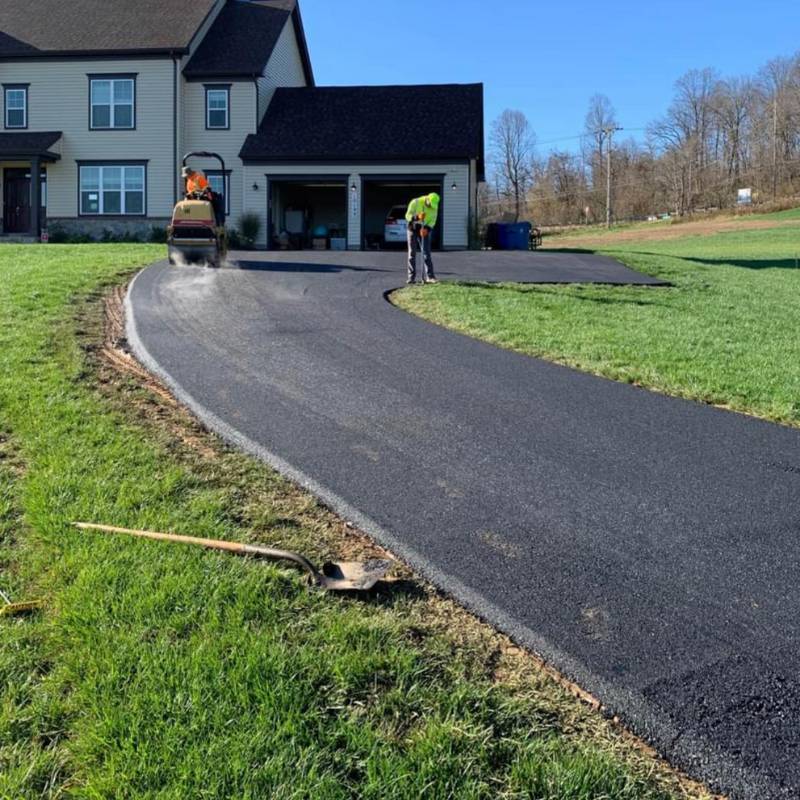 Copy-of-ceemitemplate-800-800-27 Two workers paving a curved driveway in front of a suburban house on a sunny day.