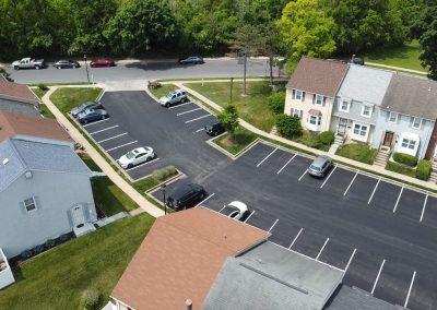 Aerial view of a residential neighborhood with parked cars and empty parking spaces along townhouses.