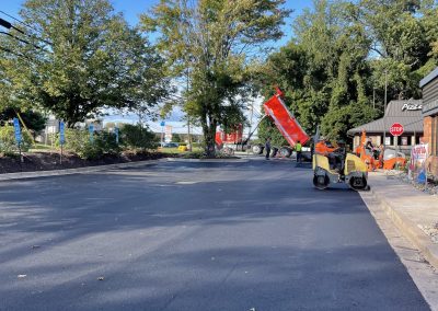 Freshly paved parking lot with construction equipment and workers under a clear blue sky.